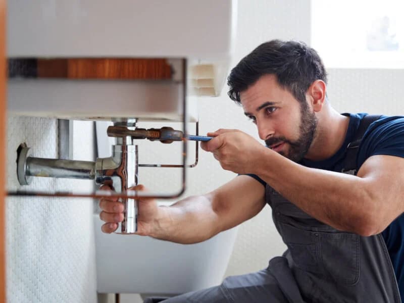 Emergency plumber fixing a pipe leak under a sink in a Lewisham property