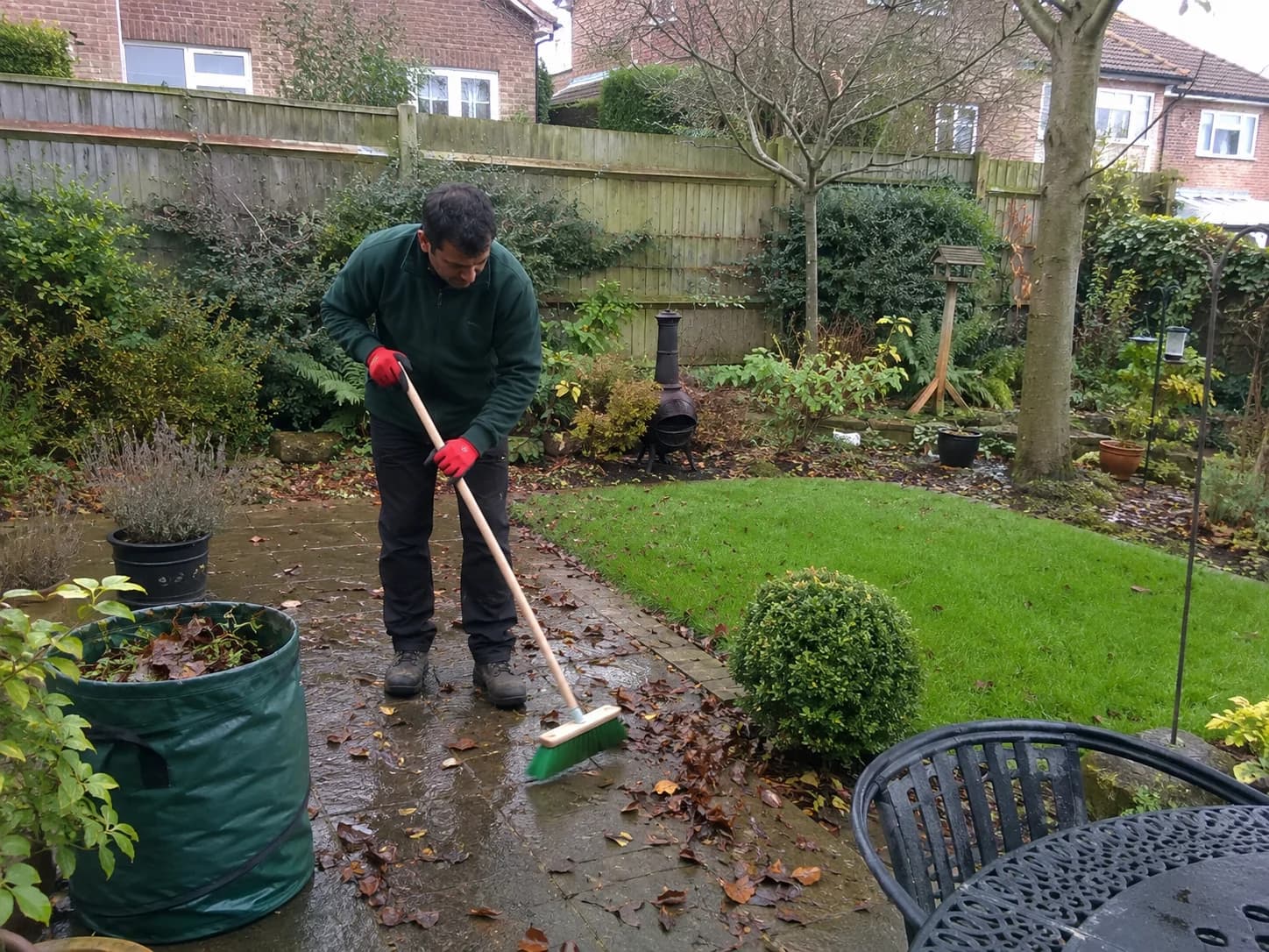 Gardener mowing lawn and trimming hedges at a London property